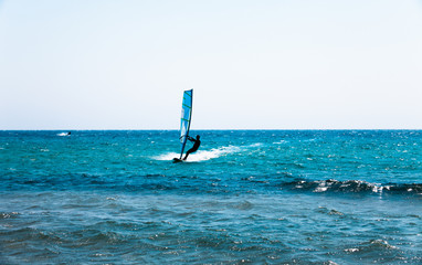 Holiday concept image with the blue sea and the blue sky. Man on the surfing board riding on the waves. Action sport on the water waves. Surfer on the surfing board.