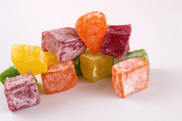 A photo of pieces of red, green, yellow and orange lacum close up