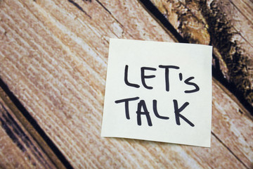 Lets talk concept words on the wooden bark background. Handwritten words on the white paper with...