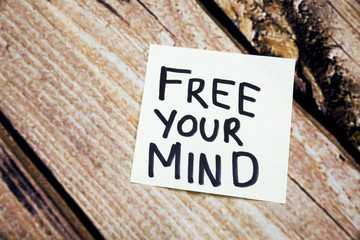 Free your mind handwritten message on the white paper with wooden background concept. Positive minds conceptual image. Flat lay above paper and wooden background.