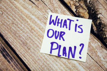 Handwritten What is our plan positive conceptual words on white paper with retro wooden bark...