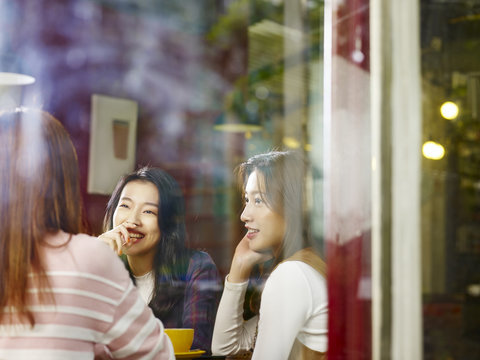 three young asian women chatting talking in coffee shop