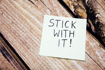 Handwritten motivational message on the white paper. Stick with it message on the paper with retro...