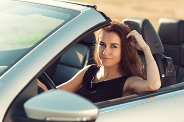 young girl driving cabrio car, on sunset light