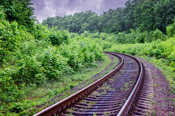 Obraz premium Railway track with turn going in distance. Excellent rail journey. Railroad runs through forest_