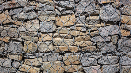 Stone wall in a metal grid as a background