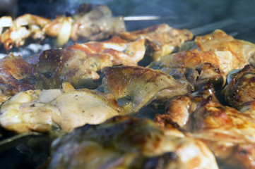 Large pieces of chicken meat in a smoke on the grill