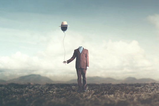 man without head holds black balloon with hat surreal concept
