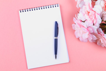 Empty notebook with blue pen on a pink pastel background. mock-up, frame, template.