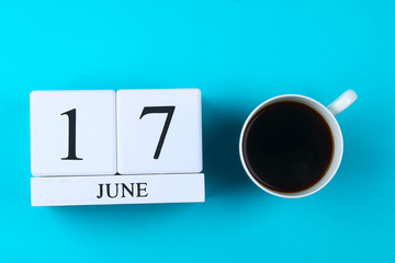 A wooden notebook with a date on June 17 and a coffee mug on a blue pastel background. Father's Day.