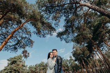 Two lovers against the forest. Just married couple is hugging. Happy couple hugging and enjoying each other walking around the park. Loving couple laughing and having fun relaxing