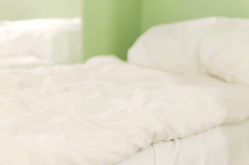 white crumpled bed in a hotel at morning, defocused