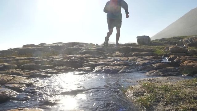 Male jogger running through muddy puddles on a rocky path by the sea