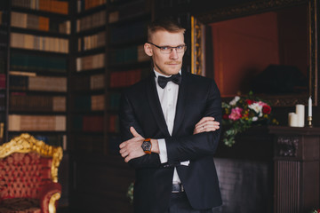 Morning of the groom. Groom morning preparation. Young and handsome groom getting dressed in a wedding shirt