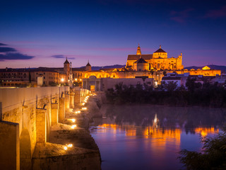 Fototapeta premium Great Mosque - Cathedral of Cordoba, iluminated. Mezquita. Roman bridge over Guadalquivir river at night.