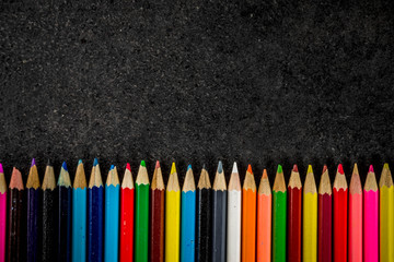 Back to school concept with books, alarm clock, color pencils, chalkboard background