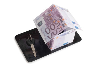 Paper house made of banknotes on a tablet on a white background