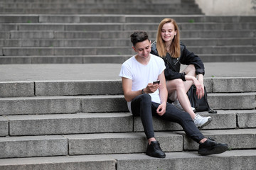 A beautiful red haired girl and a brunette guy saw something interesting in their mobile phone