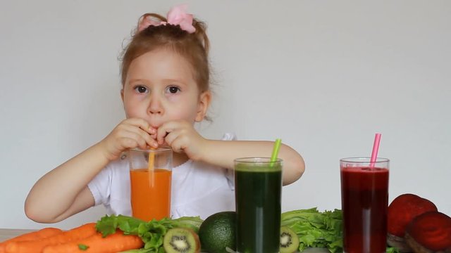 Girl child drinks vegetable smoothies - Carrot, beet and green. Detox.