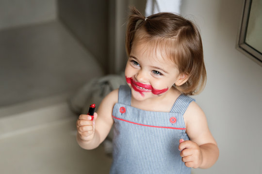 Happy little girl with smeared lipstick on face