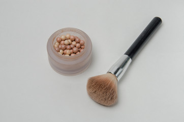 Women's cosmetics, highlighter pearls and makeup brush on white background. Decorative cosmetics