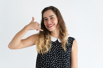 Fototapeta premium Smiling pretty young woman making call me gesture and looking at camera. Communication concept. Isolated front view on white background.