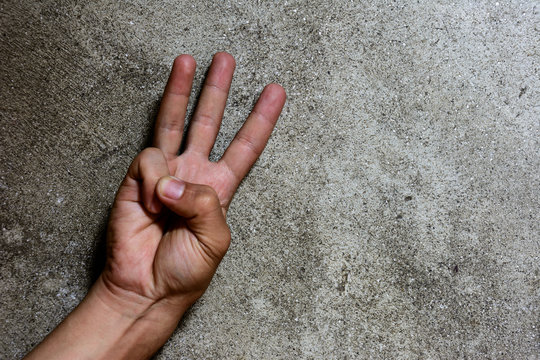 Three finger solute isolated on cement wall, hand language