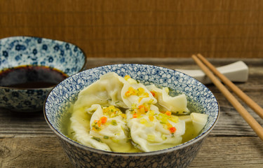 Dumpling soup with soy sauce. Fresh wonton soup and soy sauce with chopsticks. 