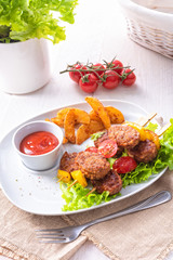 Meatballs skewers of tomato, paprika and baked potato quarters