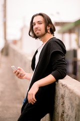 Side view image of nice boy holding smartphone in hand. Waiting for girl.