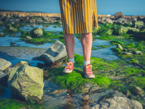 Feet and legs of woman standing on rocks by the sea
