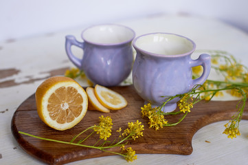 Gently purple bowl in the shape of a Bud, covered with icing. The skill of the ceramist. With yellow wildflowers, wooden Board. Morning in the village. Limon