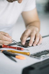 Electronics repair service. Technician disassembling smartphone for inspecting.