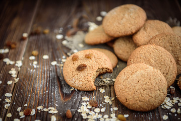 Homemade oatmeal cookies with raisins, cinnamon with milk on dark wooden background.