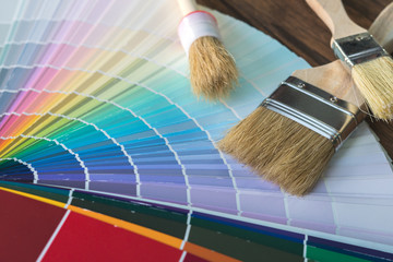 Painter and decorator work table with house project, color swatches, painting roller and paint brushes