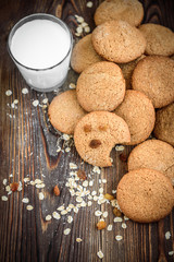 Homemade oatmeal cookies with raisins, cinnamon with milk on dark wooden background.