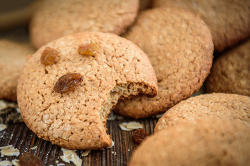 Homemade oatmeal cookies with raisins, cinnamon with milk on dark wooden background.