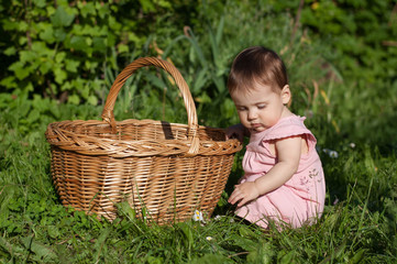 Baby is sits near the basket.