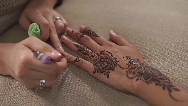 close up shot of a woman's hands, a tanned lady's hand has a mehendi for a wedding celebration, she prepares for a traditional holiday and has a charm