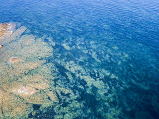 Fototapeta na wymiar Vista aerea di scogli sul mare. Panoramica del fondo marino visto dall’alto, acqua trasparente