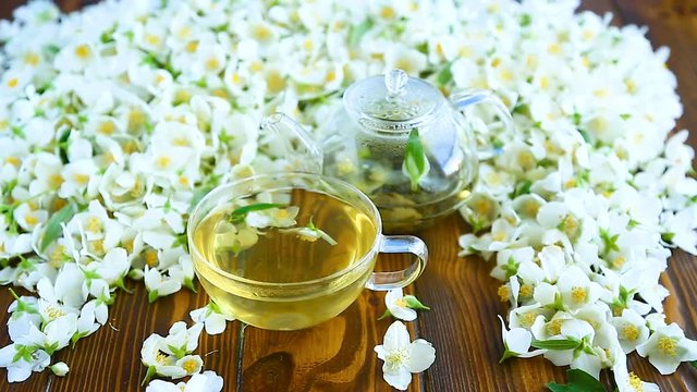 Tea with jasmine flowers in a glass teapot on a table