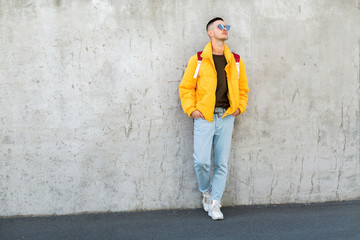 Fototapeta na wymiar fashion guy standing near a concrete wall in yellow clothes