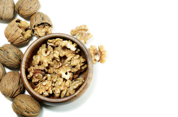 Kernel walnuts in wooden bowl with whole walnuts on isolated white background