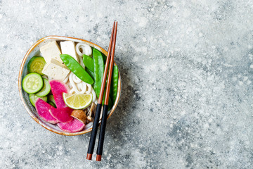 Vegan asian udon noodles soup bowl with ginger and mushrooms broth, tofu, snap peas, zucchini,...