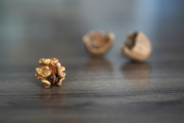 Fototapeta na wymiar One kernel walnut with its nutshell on dark walnut table background