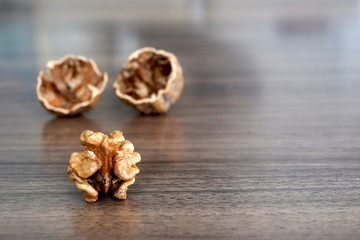 One kernel walnut with its nutshell on dark walnut table background