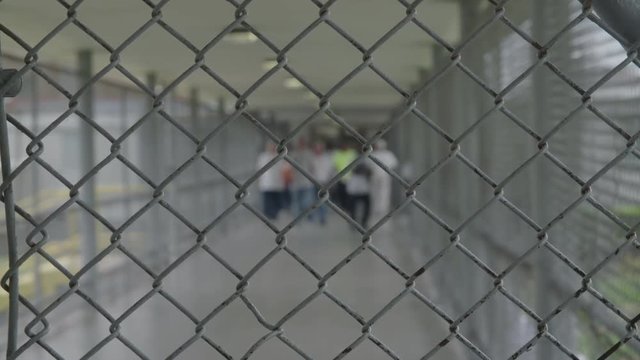 Prisoners Walking Down Alleyway Out Of Focus,, Fence In Foreground, Prison Life. Neutral Color, HD,