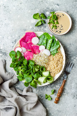 Vegan, detox Buddha bowl recipe with quinoa, snow peas, cucumber, watermelon radish, beet hummus, alfalfa seed sprouts and tahini dressing.