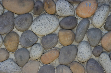 Wall of round stones with cement close-up, texture, background
