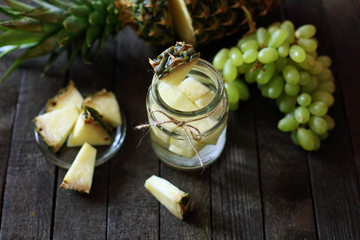 water in jar with pineapple  on wooden background